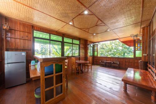 Habitación grande con suelo de madera, mesas y ventanas. en Kanecha's Home Lampang, en Lampang