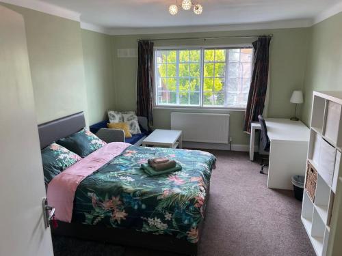 1 dormitorio con cama, escritorio y ventana en Harrow Town Centre 3 Bed Flat - Sleep up to 5 people, close to London Underground, en Harrow
