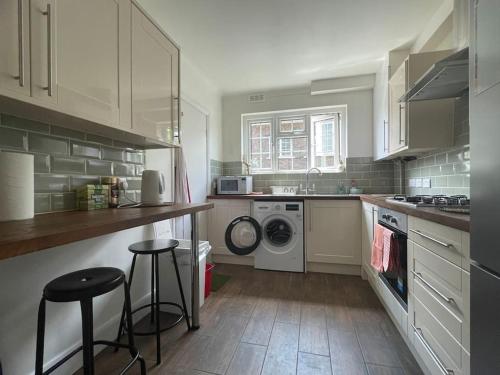 a kitchen with a washing machine and a washer and dryer at Harrow Town Centre 3 Bed Flat - Sleep up to 5 people, close to London Underground in Harrow