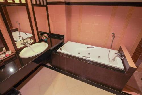 Arawan Riverside Hotel في باكسي: حمام مع حوض استحمام ومغسلة