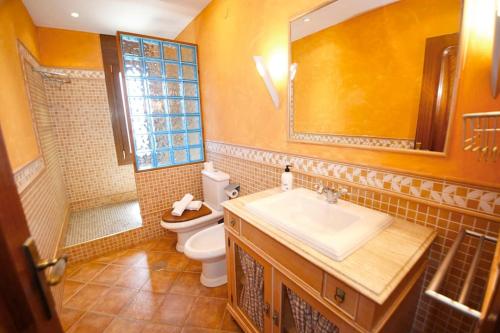 La salle de bains est pourvue d'un lavabo, de toilettes et d'un miroir. dans l'établissement Great home with AC, pool and BBQ, à El Campello