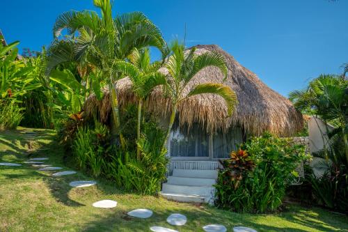 uma pequena casa com telhado de palha e palmeiras em Gravity Eco Boutique Hotel - Adults Only em Uluwatu