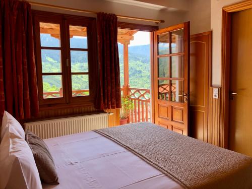 a bedroom with a bed and a large window at Apostolos Hotel in Metsovo