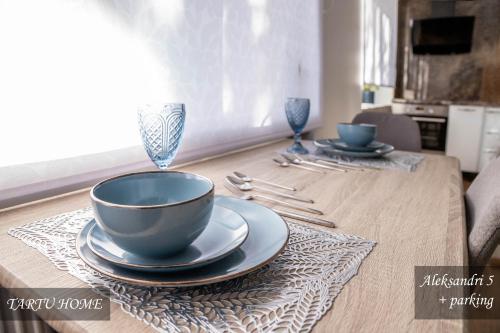 a wooden table with two blue cups and plates on it at City Center Turu str apartments, parking, Tartu Home in Tartu
