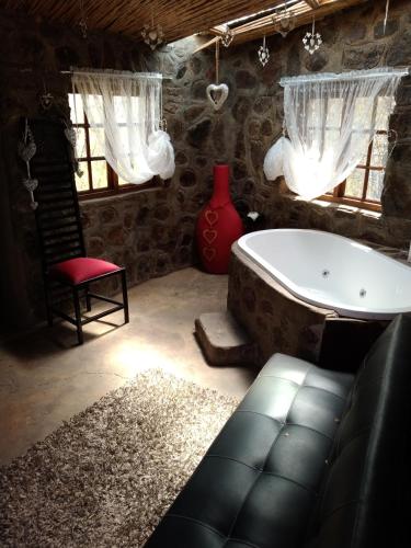 a bathroom with a bath tub and a red vase at umbabala bush camp in Rustenburg
