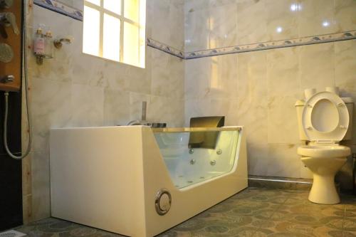 een badkamer met een bad, een toilet en een wastafel bij Brooks Lodge in Nakuru