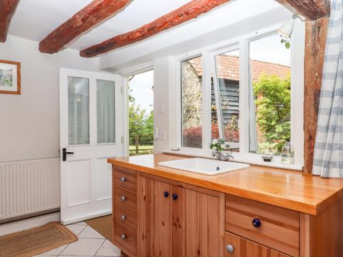 a bathroom with a sink and two windows at Shillings Cottage in Cullompton