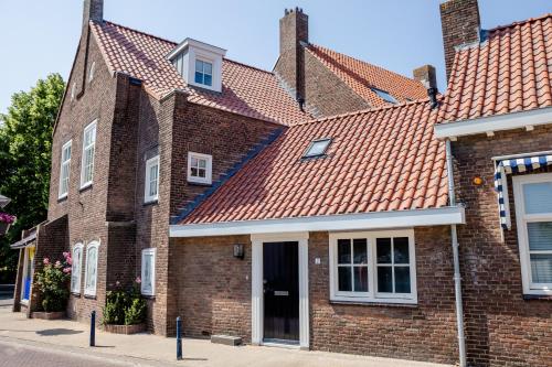 a brick house with a red roof at Prachtig 6-persoons appartement in Yerseke