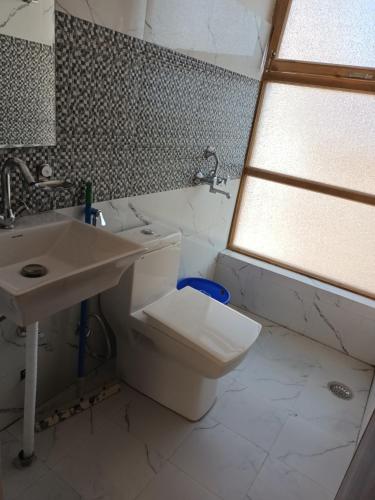 a bathroom with a sink and a toilet and a window at Gonbo Guest House in Leh