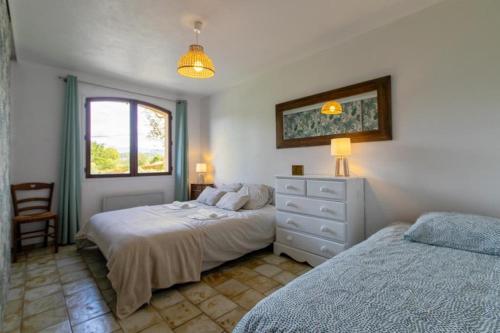 1 Schlafzimmer mit 2 Betten, einer Kommode und einem Fenster in der Unterkunft Villa provençale avec piscine et jardin au calme in Opio