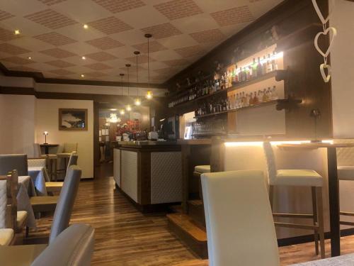 a restaurant with a bar with white chairs at Albergo Bernard in Canazei