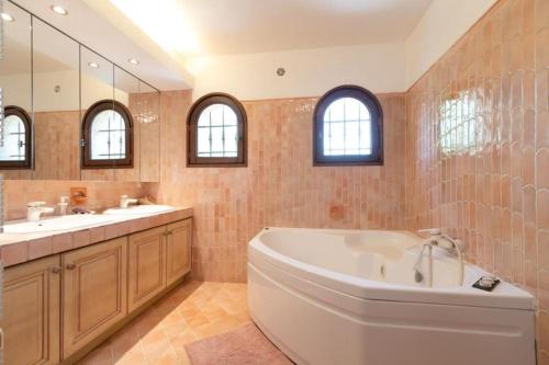 ein Badezimmer mit einer Badewanne, 2 Waschbecken und einem Spiegel in der Unterkunft Villa provençale avec piscine et jardin au calme in Opio