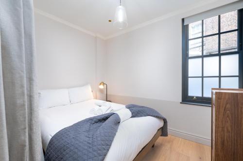 Schlafzimmer mit einem Bett mit weißer Bettwäsche und einem Fenster in der Unterkunft Trendy London Home GS1 in London
