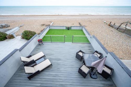 a boardwalk with tables and chairs on the beach at Beach View Breeze Family Holiday Home on the Shore in Pevensey