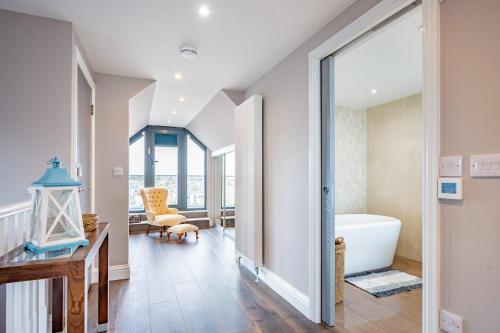a bathroom with a tub and a table and a chair at Beach View Breeze Family Holiday Home on the Shore in Pevensey