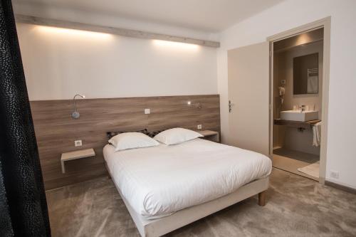 a bedroom with a white bed with a wooden headboard at Hotel Les Voyageurs in Modane