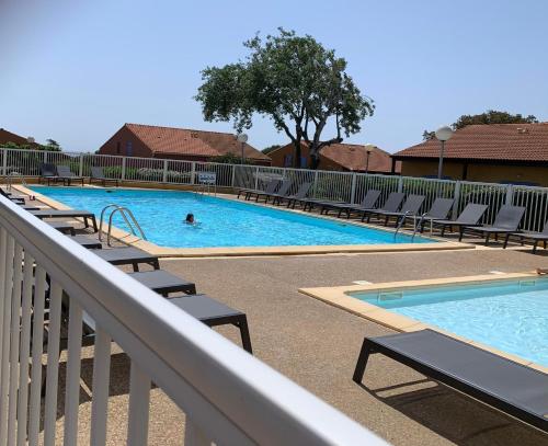 - une piscine avec des chaises et une personne dans l'eau dans l'établissement Pavillons 7 et 56 Narbonne Plage, à Narbonne-Plage