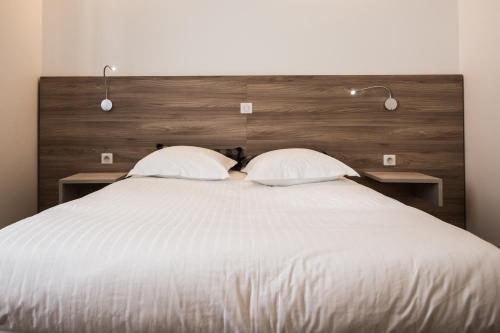 a bedroom with a large white bed with two pillows at Hotel Les Voyageurs in Modane