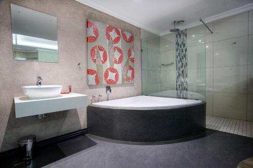 y baño con bañera, lavamanos y ducha. en Hotel Savoy and Conference Centre, en Mthatha