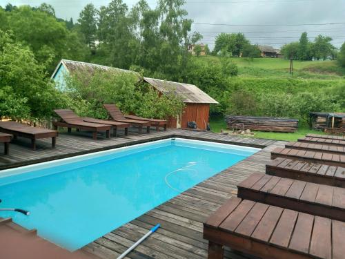 uma piscina com bancos e um deque de madeira em Між Тростяном та рікою em Slavske