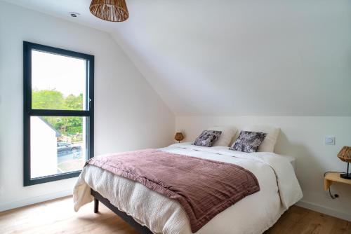 um quarto branco com uma cama e uma janela em Ti Menhir - Charmante maison pour 6 avec jardin em Plomelin
