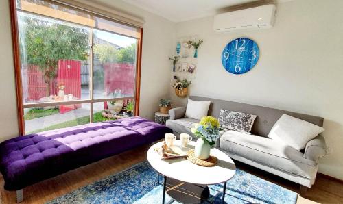 a living room with a purple couch and a table at Beach Garden Getaway in Cheltenham