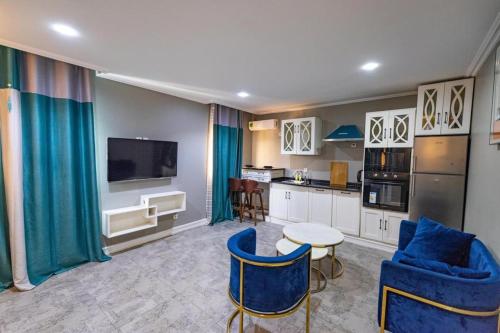 sala de estar con sillas azules y cocina en Villa Magnum, en Douala
