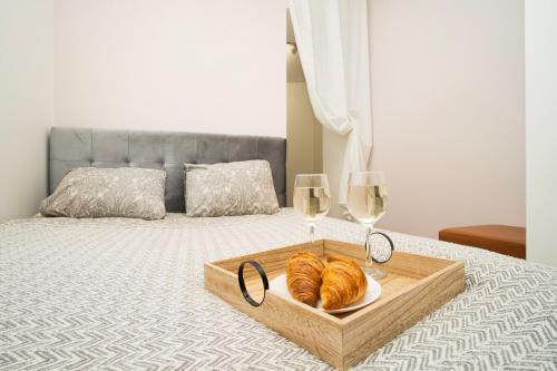 a tray of croissants and glasses of wine on a bed at Downhill Apartment on the Groundfloor in Kaunas