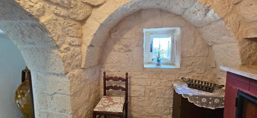 a room with a stone wall with two chairs and a window at Trulli Giovanni e Angela in Locorotondo