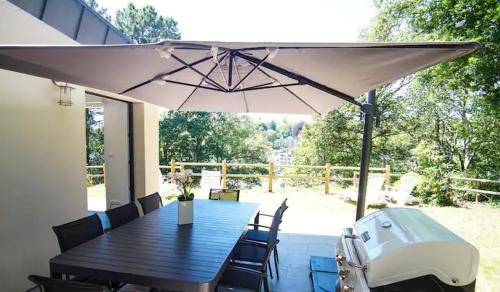 un patio avec une table et un parasol dans l'établissement Le Fusain - Maison climatisée pour 6, à Pont-Aven