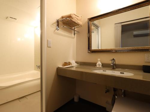 a bathroom with a sink and a mirror and a tub at Ryokan Karasawa in Kanazawa
