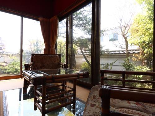 a room with a chair and a table and windows at Ryokan Karasawa in Kanazawa