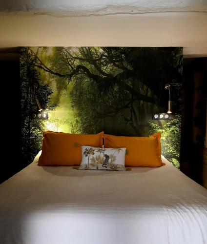 - un lit avec des oreillers orange et une peinture d'un arbre dans l'établissement Chez Joy, à Roquebrune-sur Argens