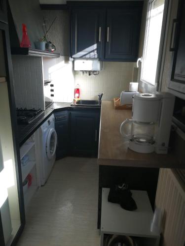 une petite cuisine avec des armoires bleues et un lave-linge dans l'établissement Proche du centre ville, à La Rochelle