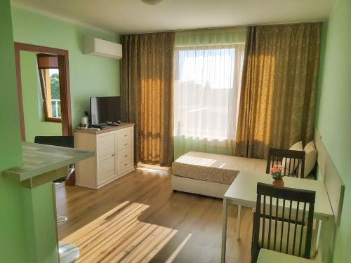 um quarto com uma cama, uma mesa e uma janela em Golden House Apartments em Golden Sands