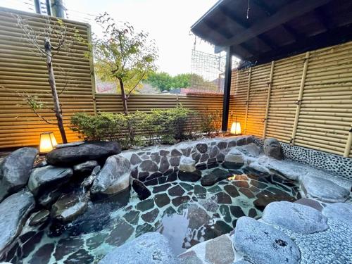 a backyard with a pond with rocks and a fence at Katsura no Izumi in Izunokuni