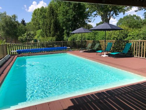 une piscine avec deux chaises et un parasol dans l'établissement Gites de Marchet, à Auvillar