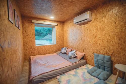 um pequeno quarto com uma cama e uma janela em แพคิงส์ราฟ เขื่อนศรีนครินทร์ กาญจนบุรี em Ban Wang Khun Knachen
