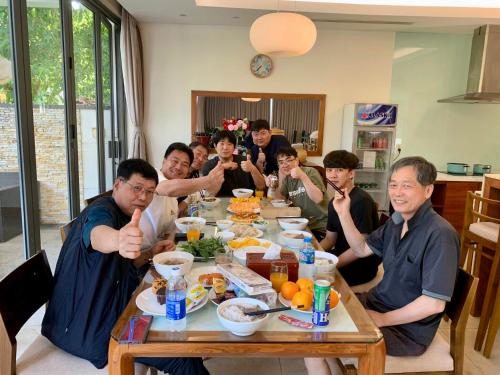 岘港Vacation Home Ocean Villas的一群坐在桌子旁吃饭的人