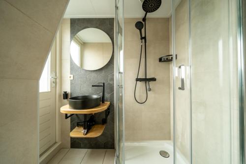 uma casa de banho com um chuveiro, um lavatório e um espelho. em Hof van Schoorl em Schoorldam