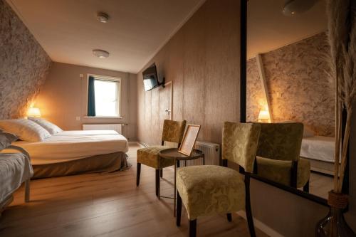 a hotel room with a bed and a chair at Hof van Schoorl in Schoorldam