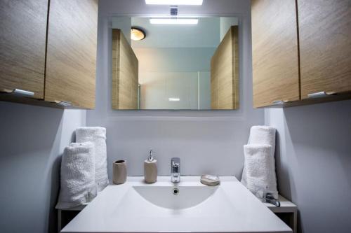 une salle de bain avec un lavabo blanc et un miroir dans l'établissement La casa du Lac YourHostHelper, à Homps