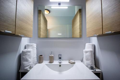 een badkamer met een witte wastafel en een spiegel bij La casa du Lac YourHostHelper in Homps