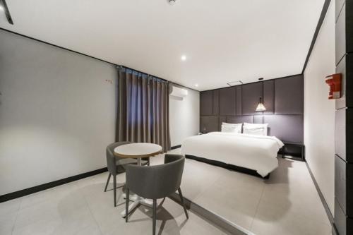 um quarto de hotel com uma cama e uma mesa e cadeira em Almond Hotel Gupo Station em Busan