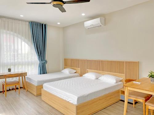a bedroom with two beds and a table and a desk at Moc Son Apartment - Attractive price for week and month stay in Danang