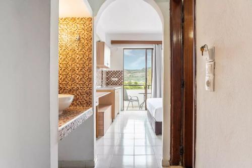 a hallway leading to a bathroom with a bed and a sink at Sotirakis Hotel in Faliraki