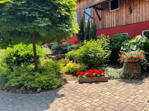 a garden with flowers and a tree and a building at Les Authentics - Le Domaine d'Autrefois & Spa in Bolsenheim
