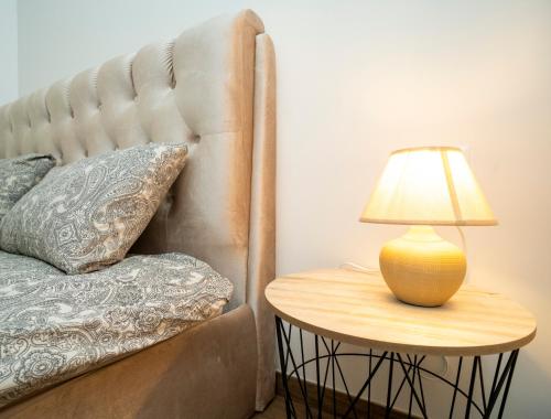 a lamp on a side table next to a bed at Downhill Apartment with a Private Terrace in Kaunas