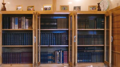 een bibliotheek met houten planken vol boeken bij Alpine Lodge And Stays in Shangarh