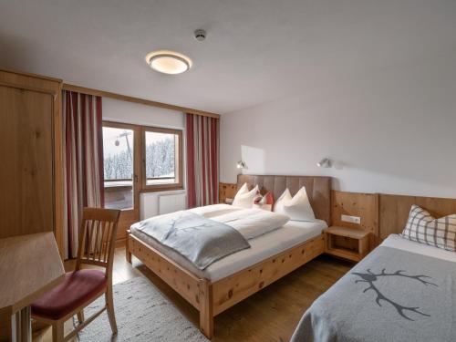 a bedroom with two beds and a chair at Berghaus Koglmoos in Auffach
